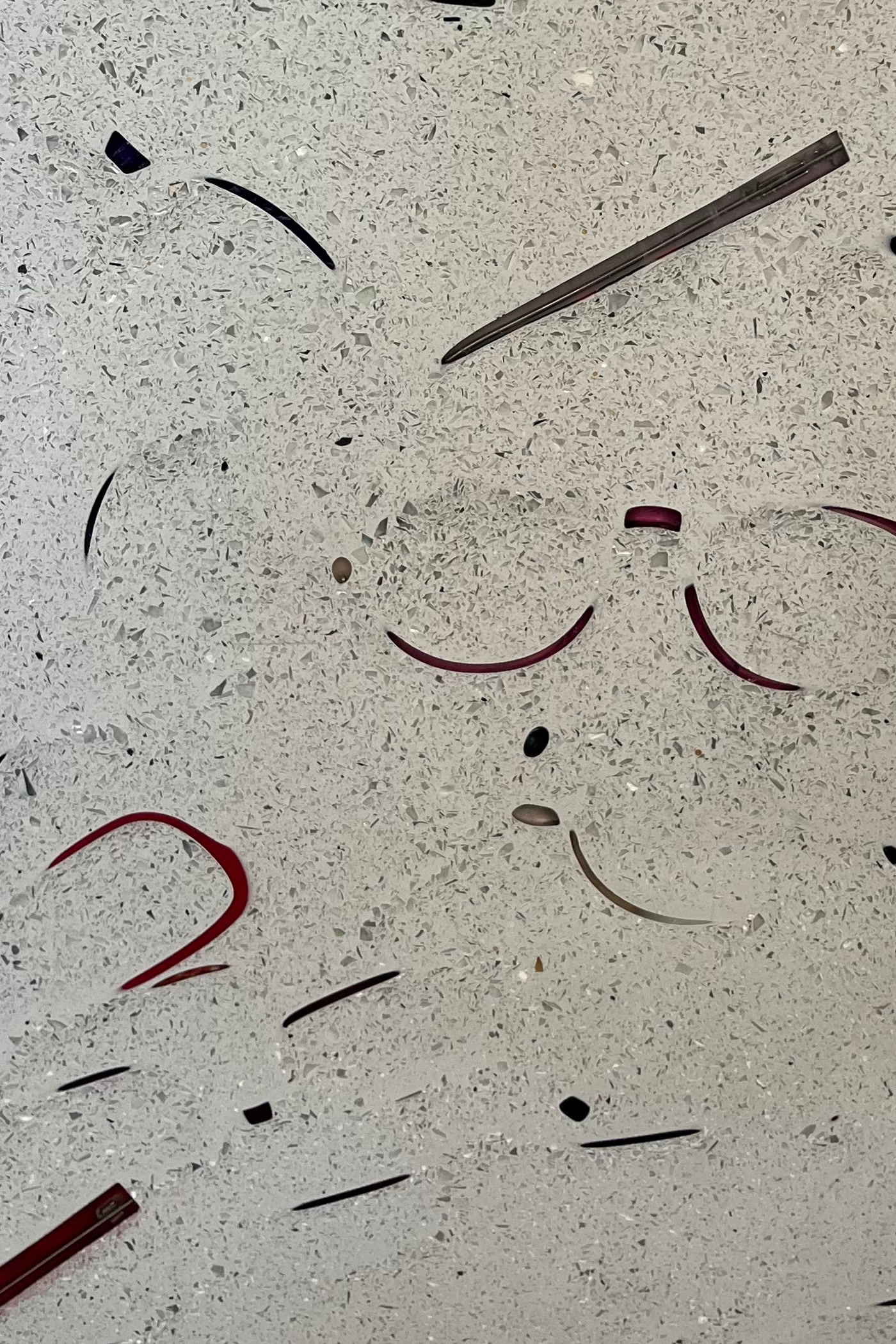 Rendu A : montures entières prises dans un fond gris pailleté, on devine les cercles rouges d’une paire de lunettes et des branches noires.