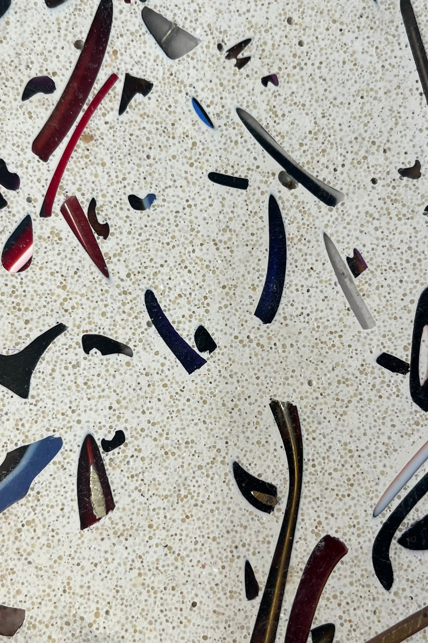 Rendu B : longs morceaux de branches de lunettes, rouges, bleus, noirs et écaille, sur un fond clair moucheté.