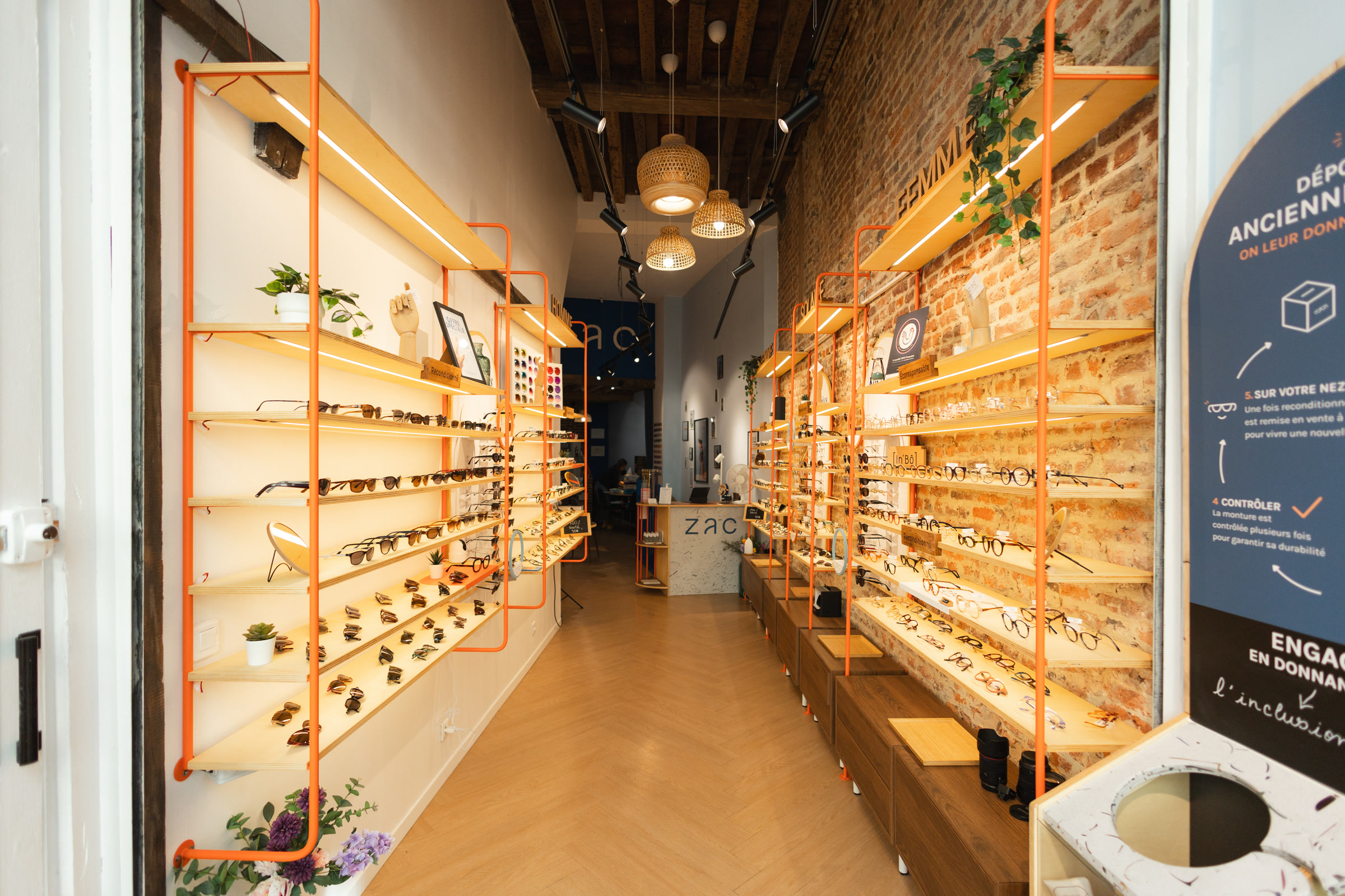 Le magasin Zac de Lille en enfilade : présentoirs en bois clair et orange, boîte de collecte en Terrazac au premier plan.
