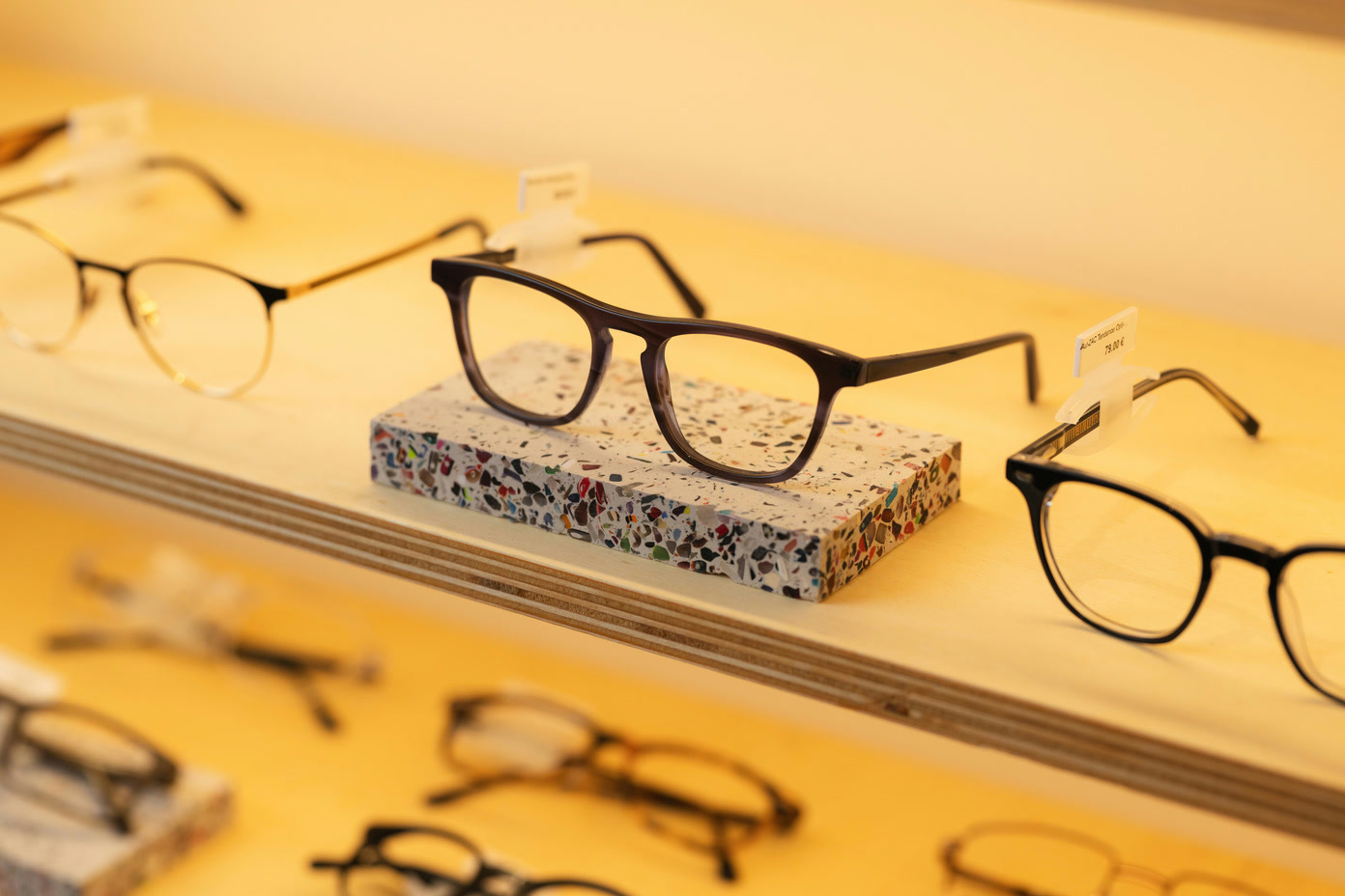 Une paire de lunettes posée sur un support en Terrazac, sur une étagère du magasin.